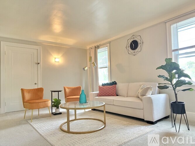 A living room with a white couch, a coffee table, and two chairs.