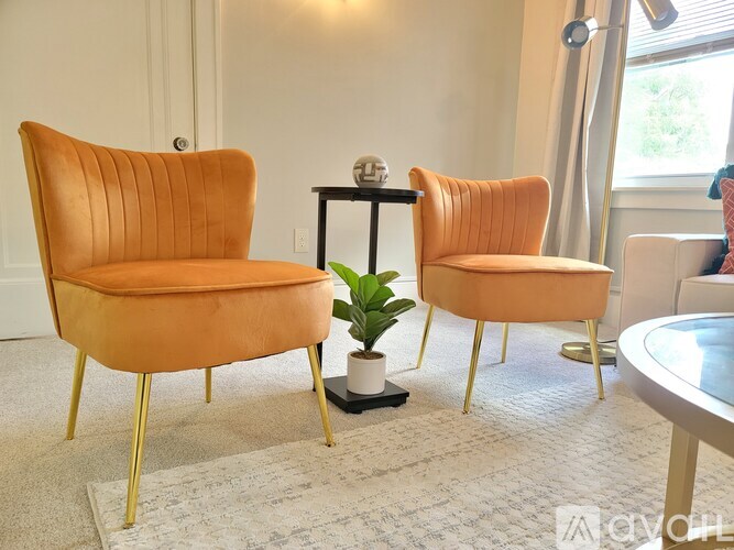 Two orange chairs with gold legs sit in a living room.