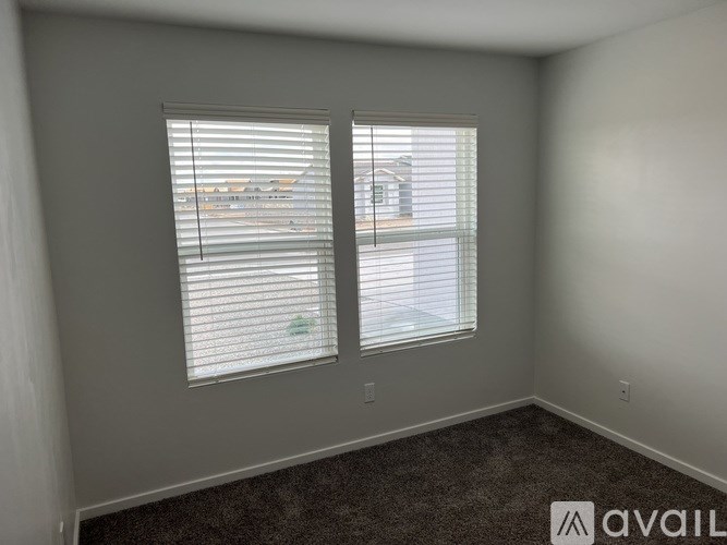 A room with two windows covered in white blinds.