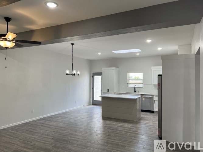 A spacious room with a kitchen area and a ceiling fan.