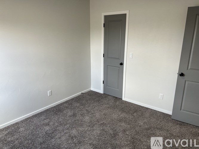 A room with a carpeted floor and two doors.
