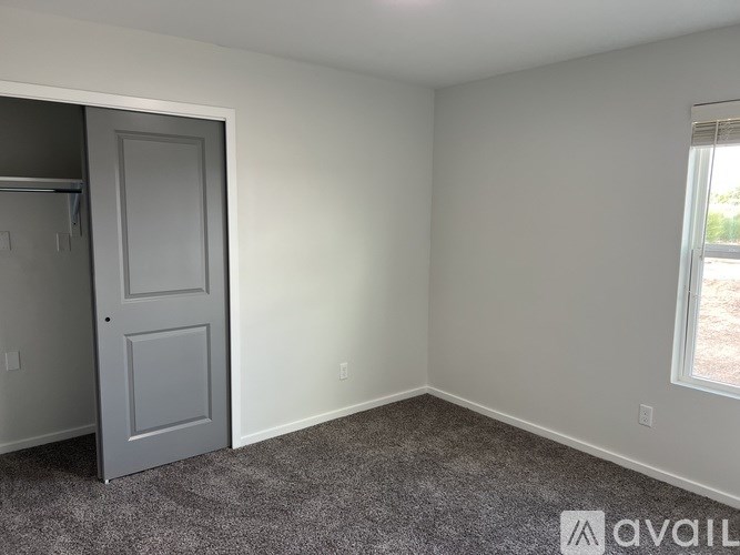 A room with a grey door and a window with a view of a yard.