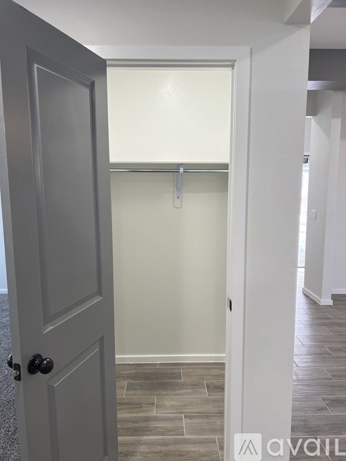 A white door with a black handle is open to a hallway.