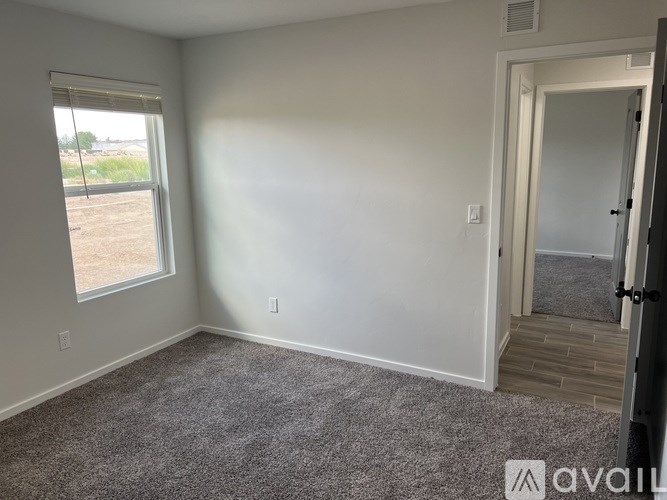 A room with a carpeted floor, a window, and a door.