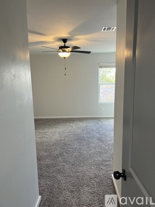 A room with a ceiling fan and carpeted floor.