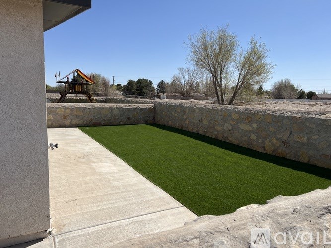 A backyard with a stone wall and a green lawn.