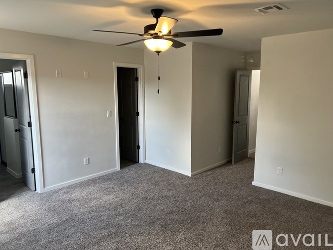 A room with a ceiling fan and carpeted floor.