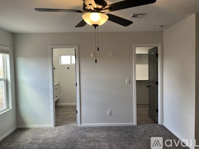 A room with a ceiling fan and carpeted floor.