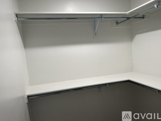 A white shelf with a metal bracket is mounted on a white wall.