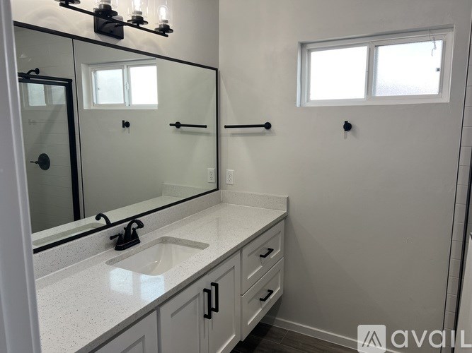 A bathroom with a sink, mirror, and a window.