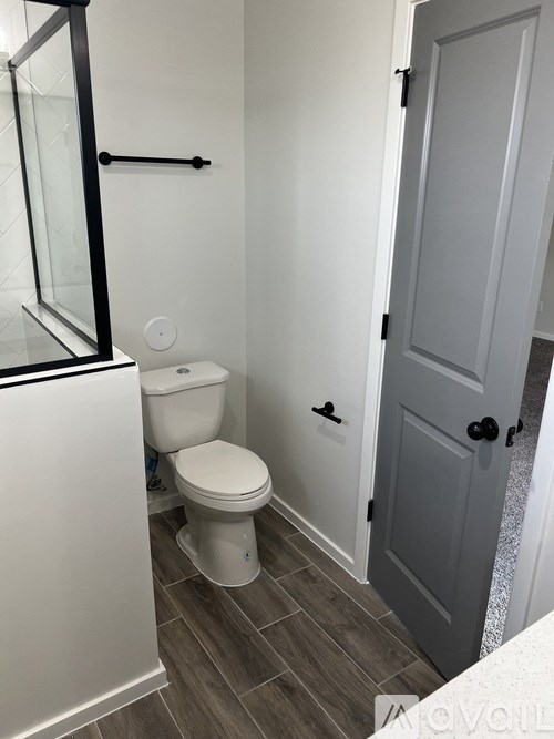 A white toilet sits in a bathroom next to a white door.