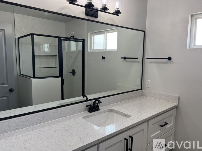 A bathroom with a sink, mirror, and a shower.