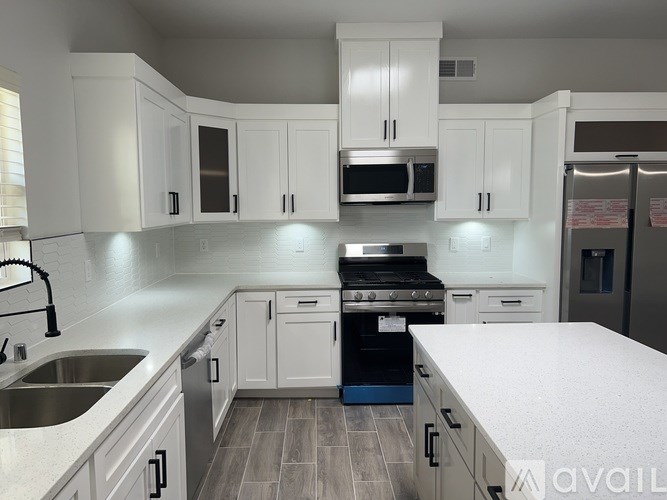 A kitchen with white cabinets and a wooden floor.