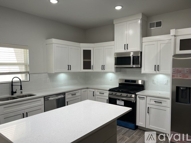 A modern kitchen with white cabinets and stainless steel appliances.