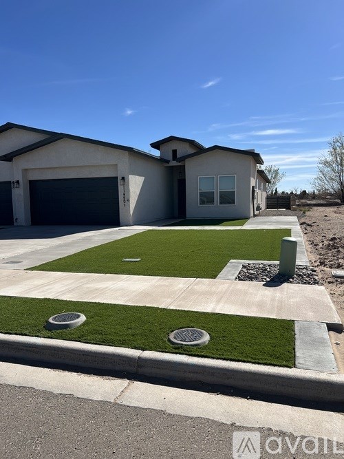 A house with a grey garage door and a white wall with a window.