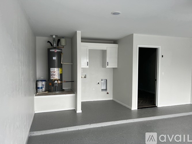 A room with a white wall and a black tank on the floor.