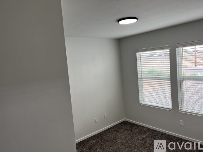 A room with a carpeted floor and a window with blinds.
