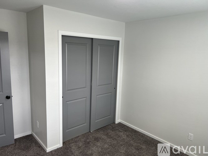 A room with a white door and two grey doors.
