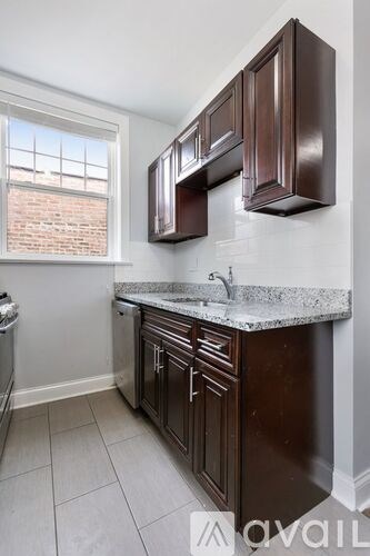 A kitchen with brown cabinets and a marble countertop.