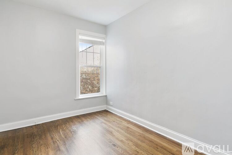A room with a window and wooden flooring.