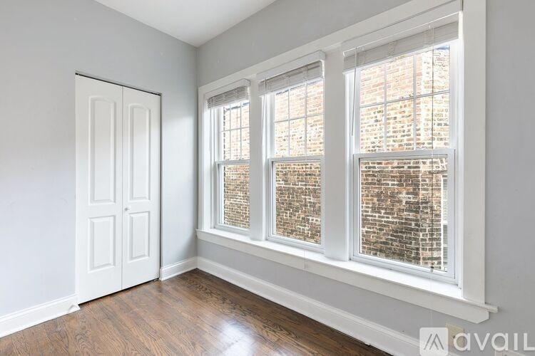 A room with a white door and a window with a brick wall view.