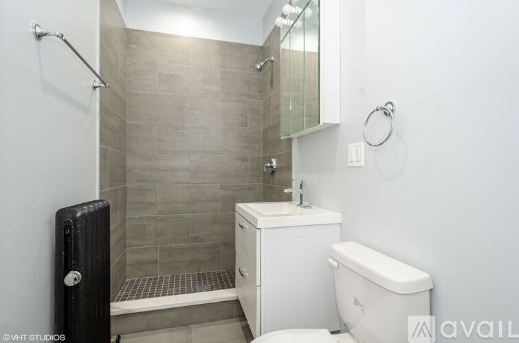 A bathroom with a white toilet, a shower with a glass door, and a black radiator.