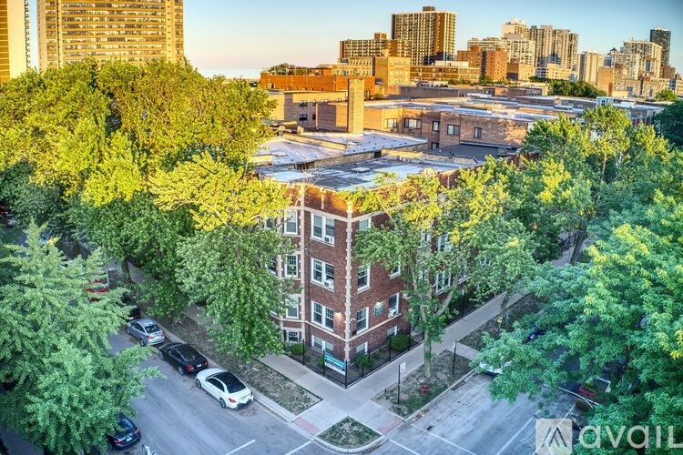 A cityscape with a mix of residential and commercial buildings, surrounded by trees and a parking lot with cars.