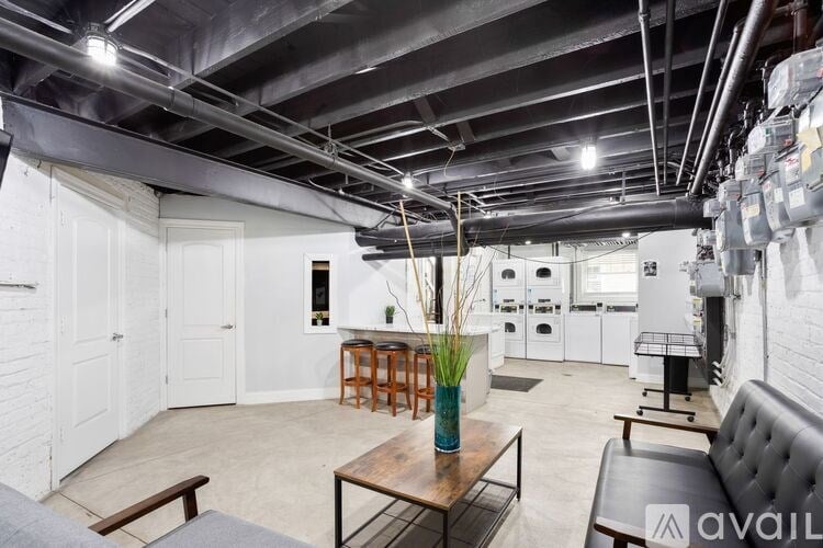 A room with a table and chairs in the foreground and a kitchen in the background.