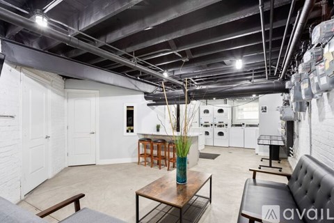 A room with a table and chairs in the foreground and a kitchen in the background.