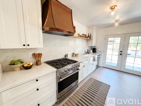 A kitchen with white cabinets and a copper hood.