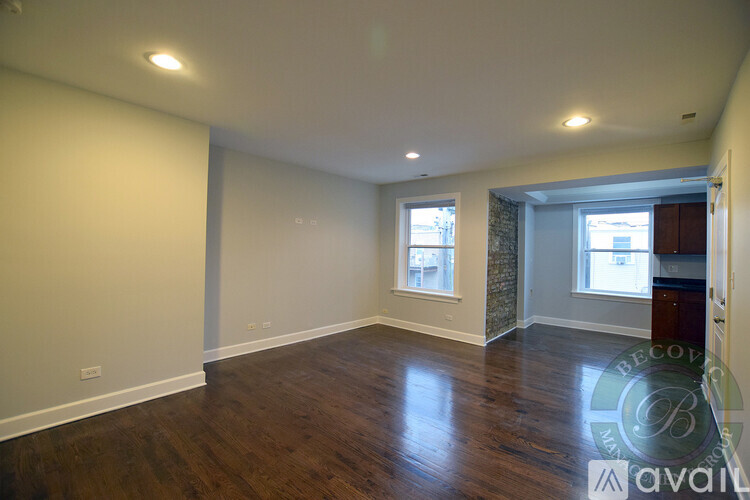 A spacious room with wooden floors and two windows.