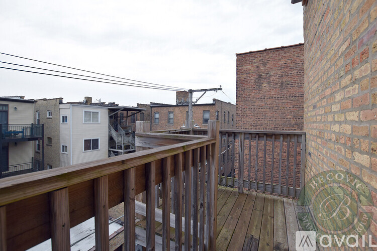 A balcony with a wooden railing overlooks a brick building and a snow-covered ground.