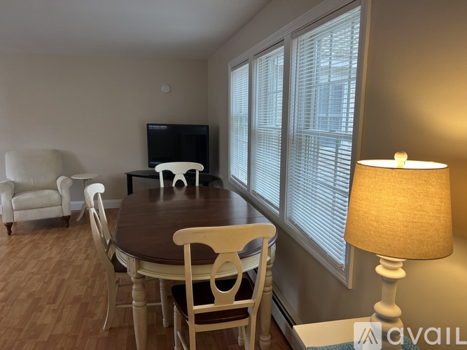 A living room with a television, a couch, a table with chairs, and a lamp.