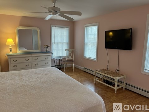 A bedroom with a bed, dresser, chair, and television.