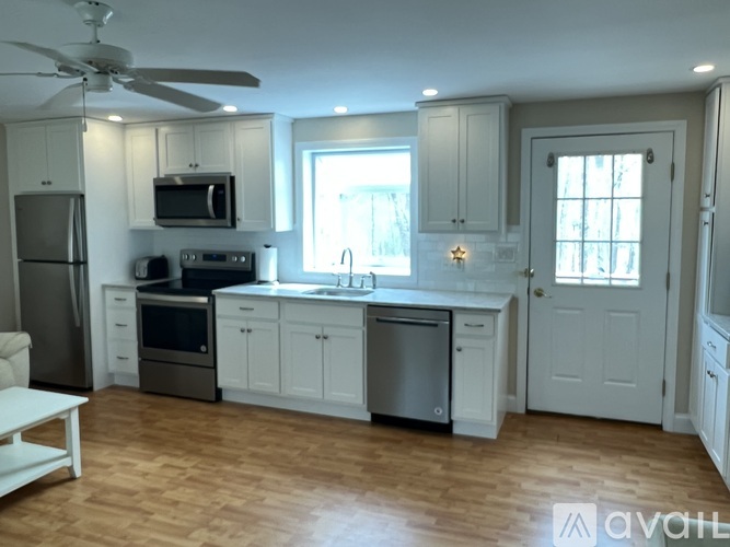 A kitchen with white cabinets and a wooden floor.