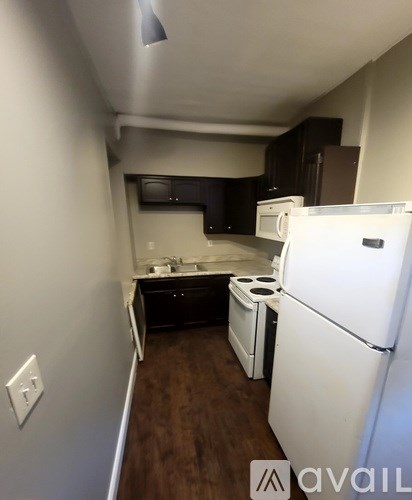 A kitchen with a white refrigerator and a white wall.