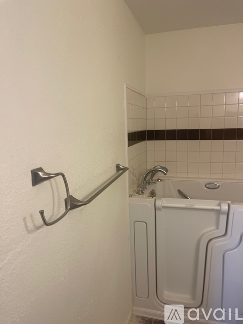 A white bathroom with a white tub and a white towel rack.