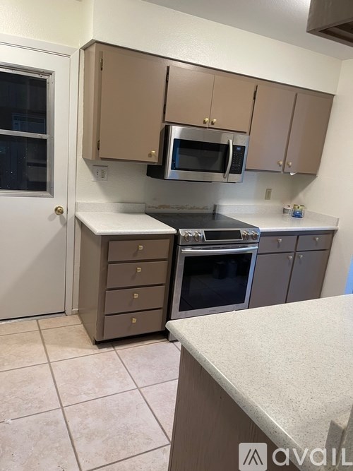 A kitchen with a white counter top and brown cabinets.