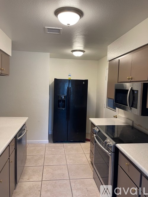 A kitchen with a black refrigerator and stainless steel appliances.