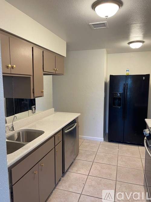 A kitchen with brown cabinets and a black refrigerator.