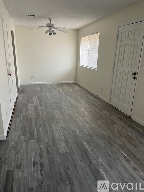 A room with a grey floor and a white ceiling fan.