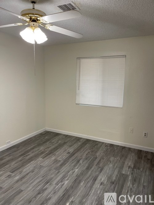 A room with a ceiling fan and a window with blinds.