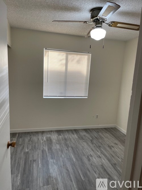 A room with a ceiling fan and a window with blinds.