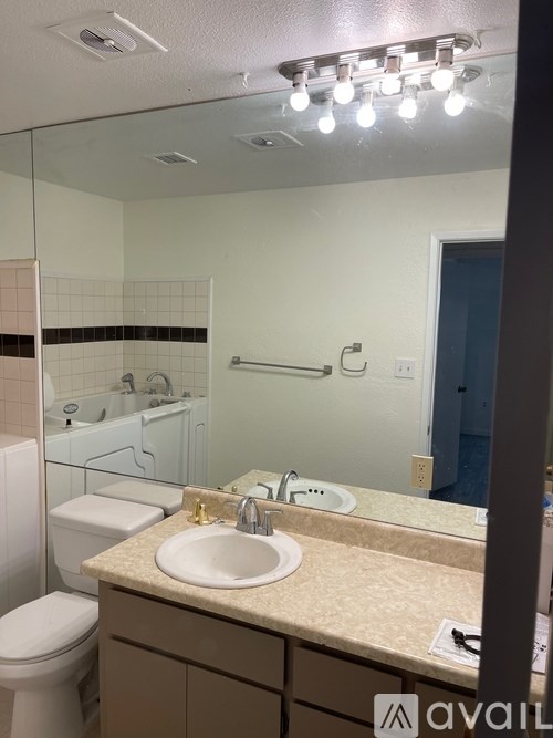 A bathroom with a sink, toilet, and mirror.