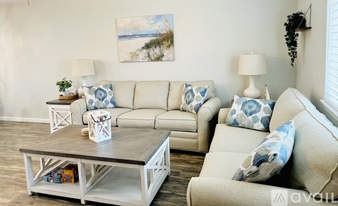 A living room with a white couch, a coffee table, and a painting on the wall.