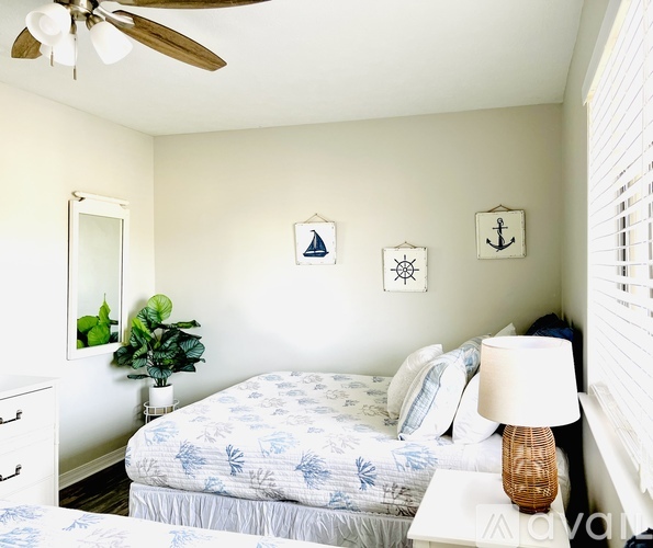 A bedroom with a bed, a ceiling fan, and a nightstand with a lamp.