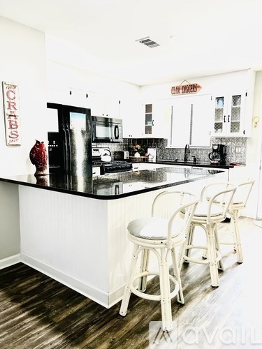 A kitchen with white chairs and a black counter.
