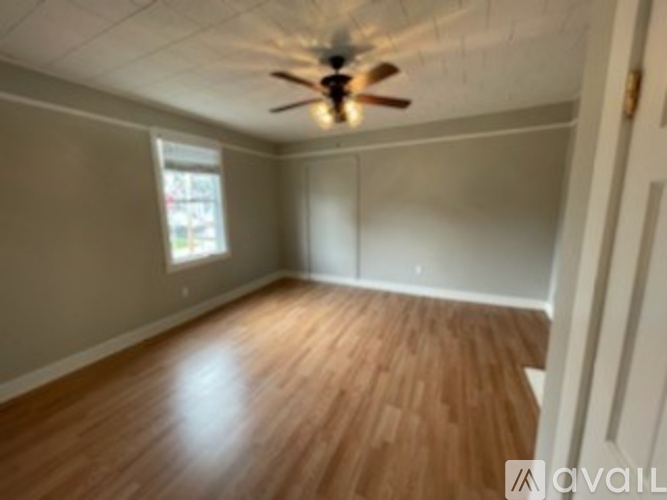 A room with a ceiling fan and wooden flooring.