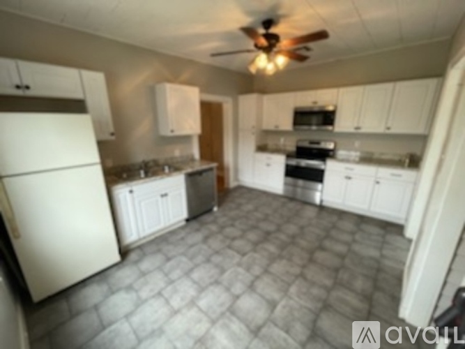 A kitchen with a white fridge and a ceiling fan.