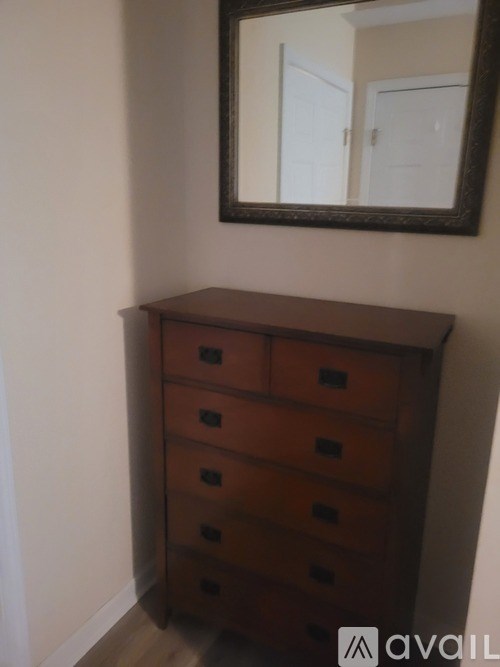 A brown chest of drawers with a mirror above it.